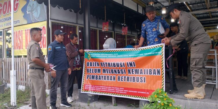 Petugas saat memasang spanduk teguran di kawasan Taman Tunggal Sangumang, Jalan Yos Sudarso.