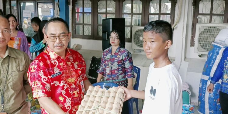 Asisten III Setda Kapuas, Perry Noah mewakili Bupati Kapuas menyerahkan bantuan atensi kepada warga.